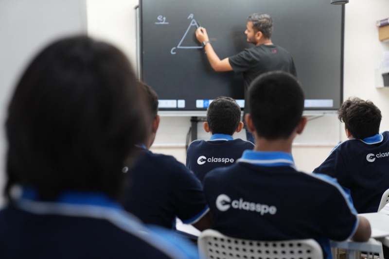 Students follow a ClassPe teacher explaining geometry on the classroom board.